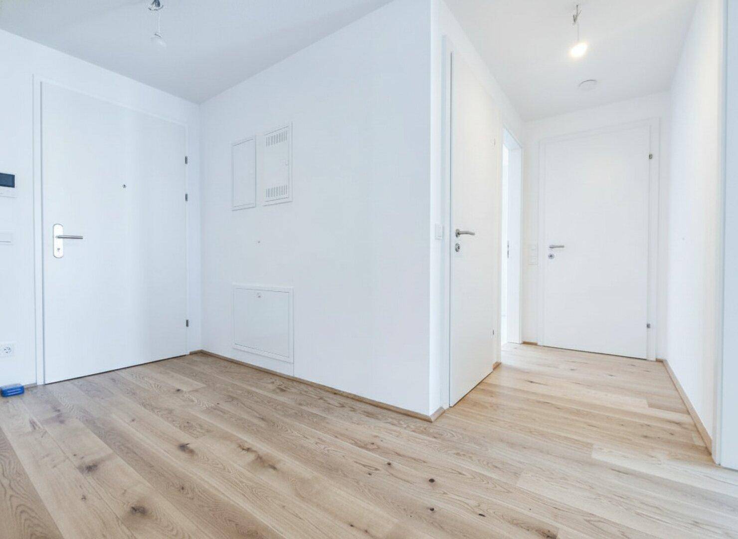 Heller Flur mit Holzboden und mehreren Türen, die zu den verschiedenen Räumen führen.
