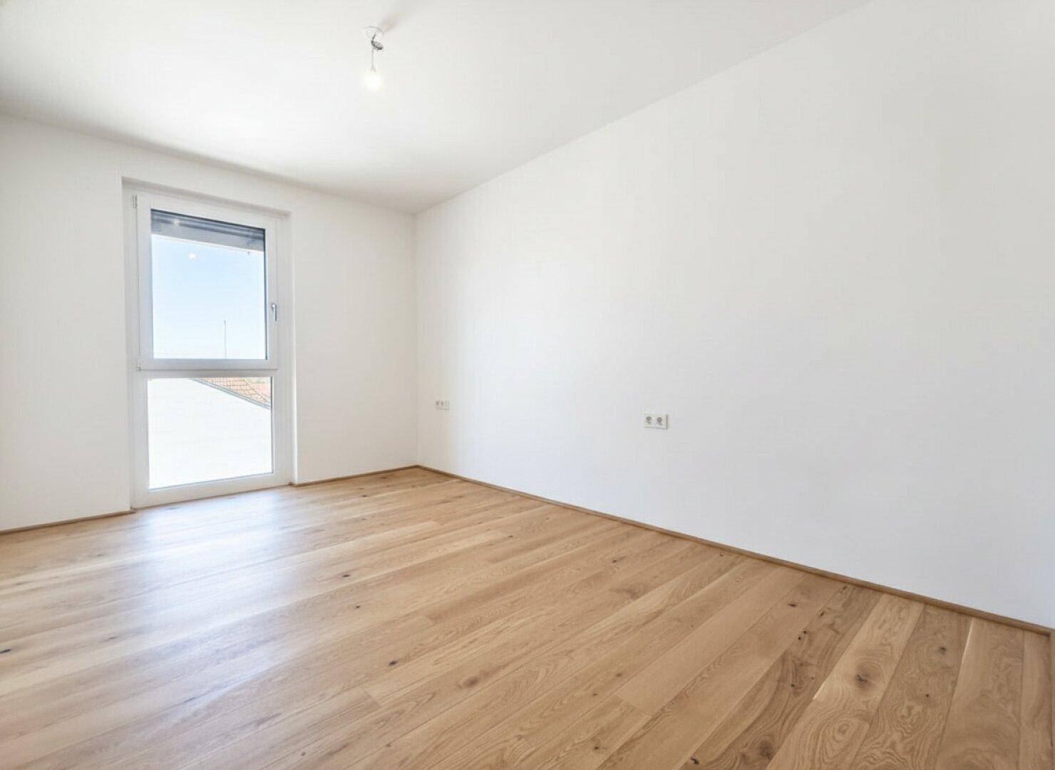 Ruhiges Schlafzimmer mit hellem Parkettboden und einem Fenster mit Rollladen für Privatsphäre.
