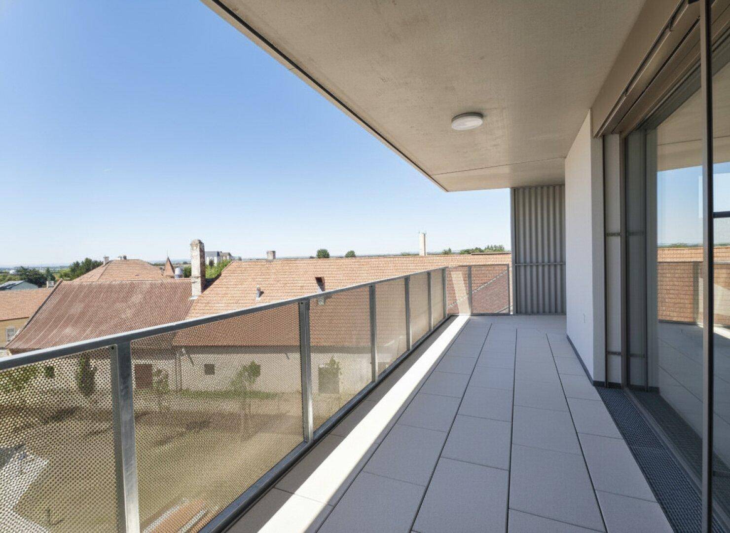 Geräumiger Balkon mit Fliesenboden und Metallgeländer, bietet einen weiten Blick über die Dächer.