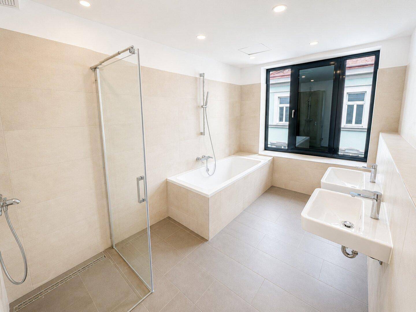 Modernes Badezimmer mit beigen Fliesen, Badewanne, begehbarer Dusche und Doppelwaschbecken.