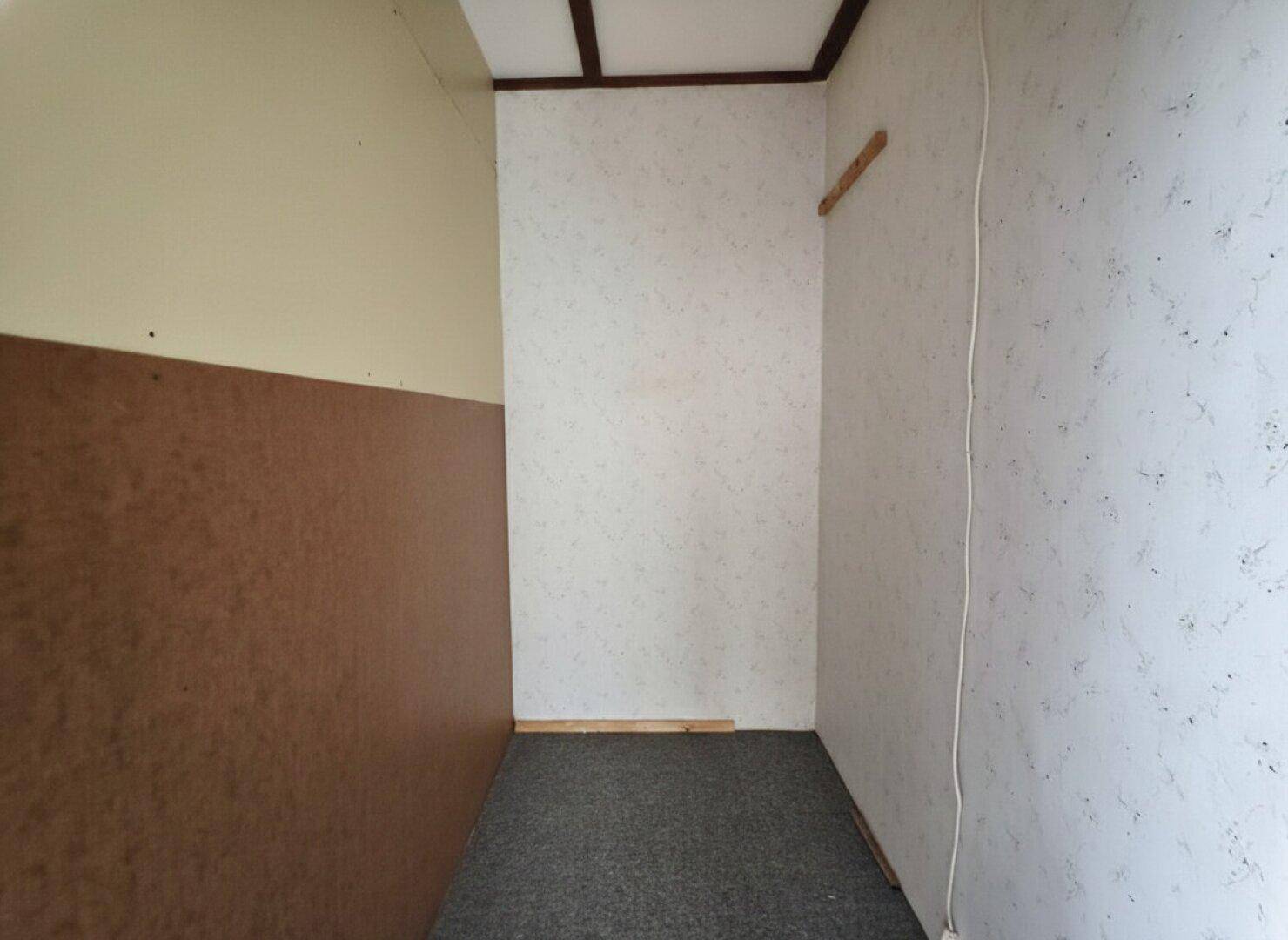 Kleiner Abstellraum mit Teppichboden und teilweise verkleideten Wänden.