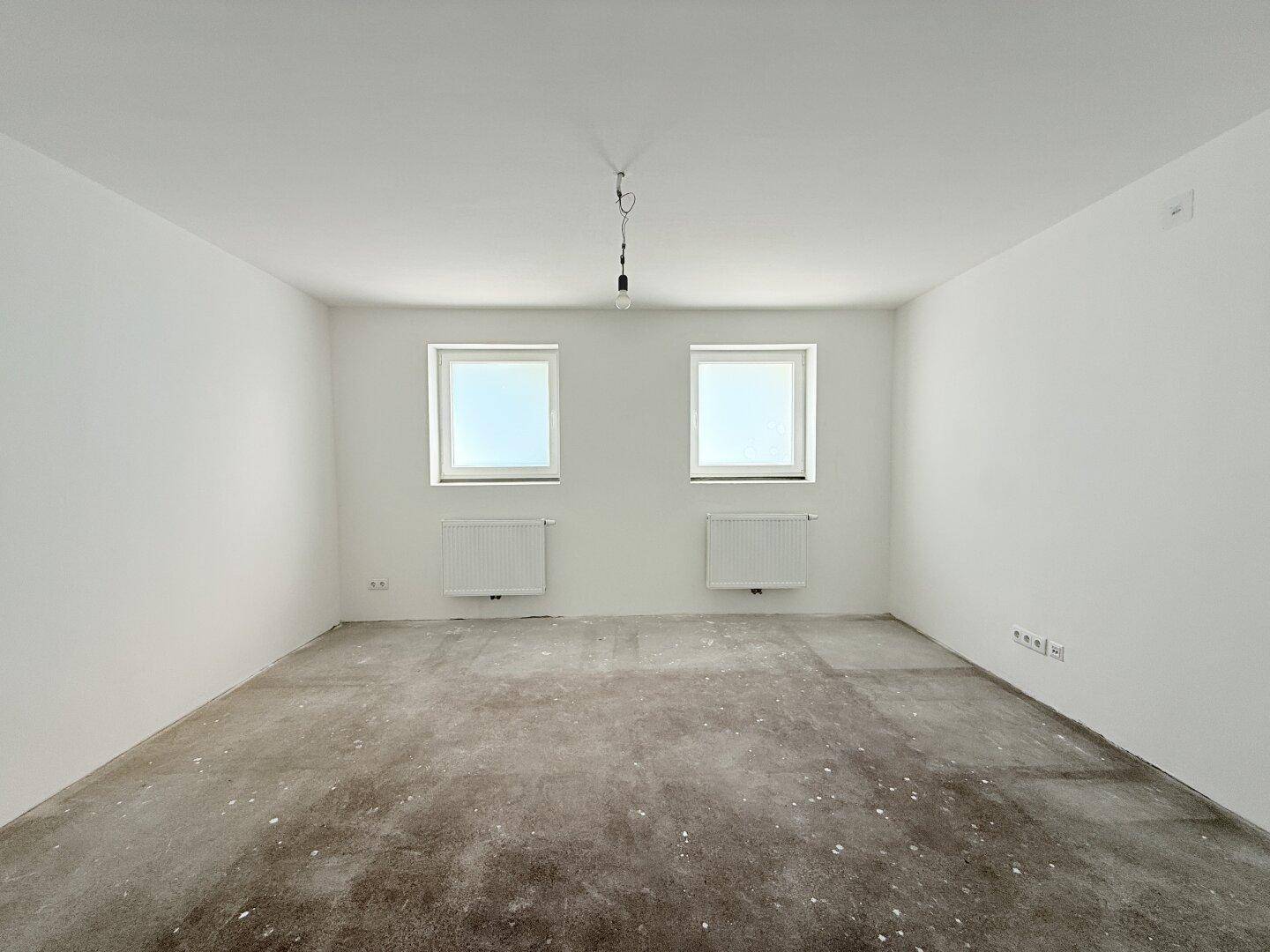 Heller, unmöblierter Raum mit zwei Fenstern und Heizkörpern, bereit für die individuelle Gestaltung.