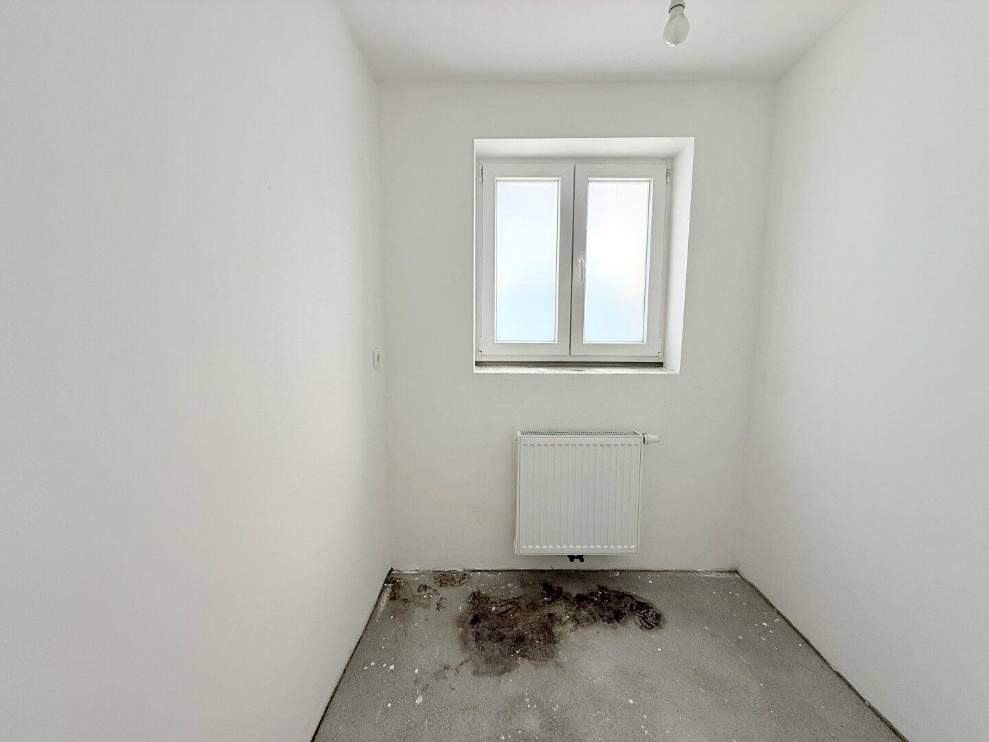 Kleiner, heller Raum mit einem Fenster und Heizkörper, ideal als Büro oder Abstellraum nutzbar.