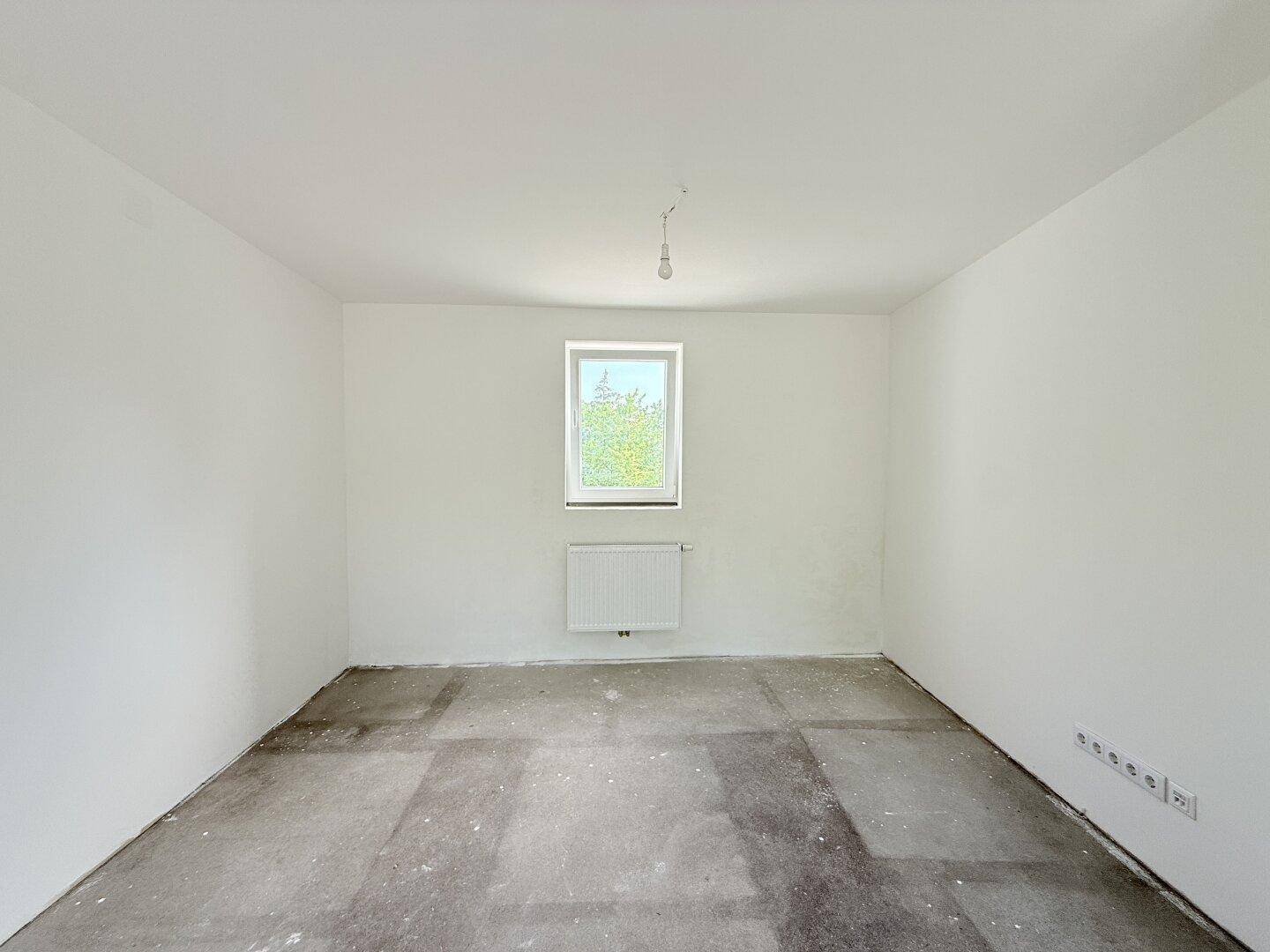 Heller, unmöblierter Raum mit einem Fenster und Heizkörper, bereit für die individuelle Gestaltung.