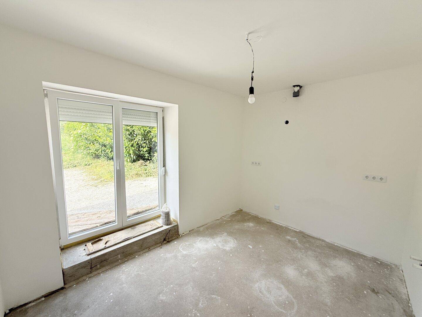 Heller, unmöblierter Raum mit großem Fenster und Rollladen, bereit für die individuelle Einrichtung.