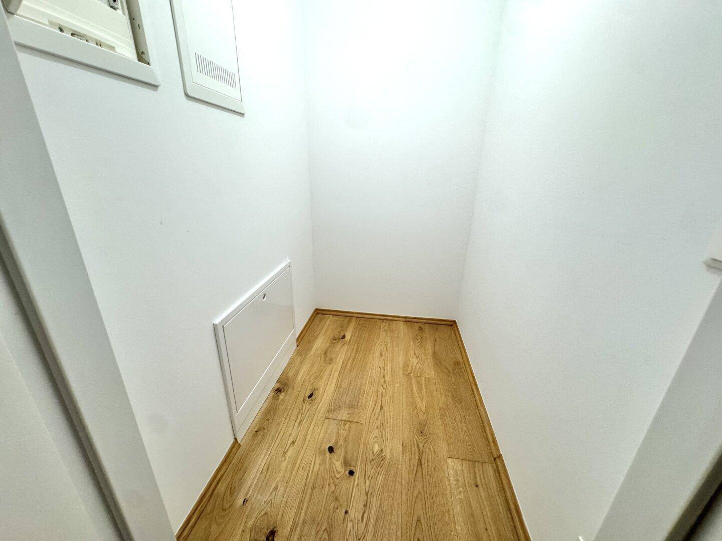 Kleiner Abstellraum mit hellem Parkettboden und weißen Wänden für zusätzlichen Stauraum.