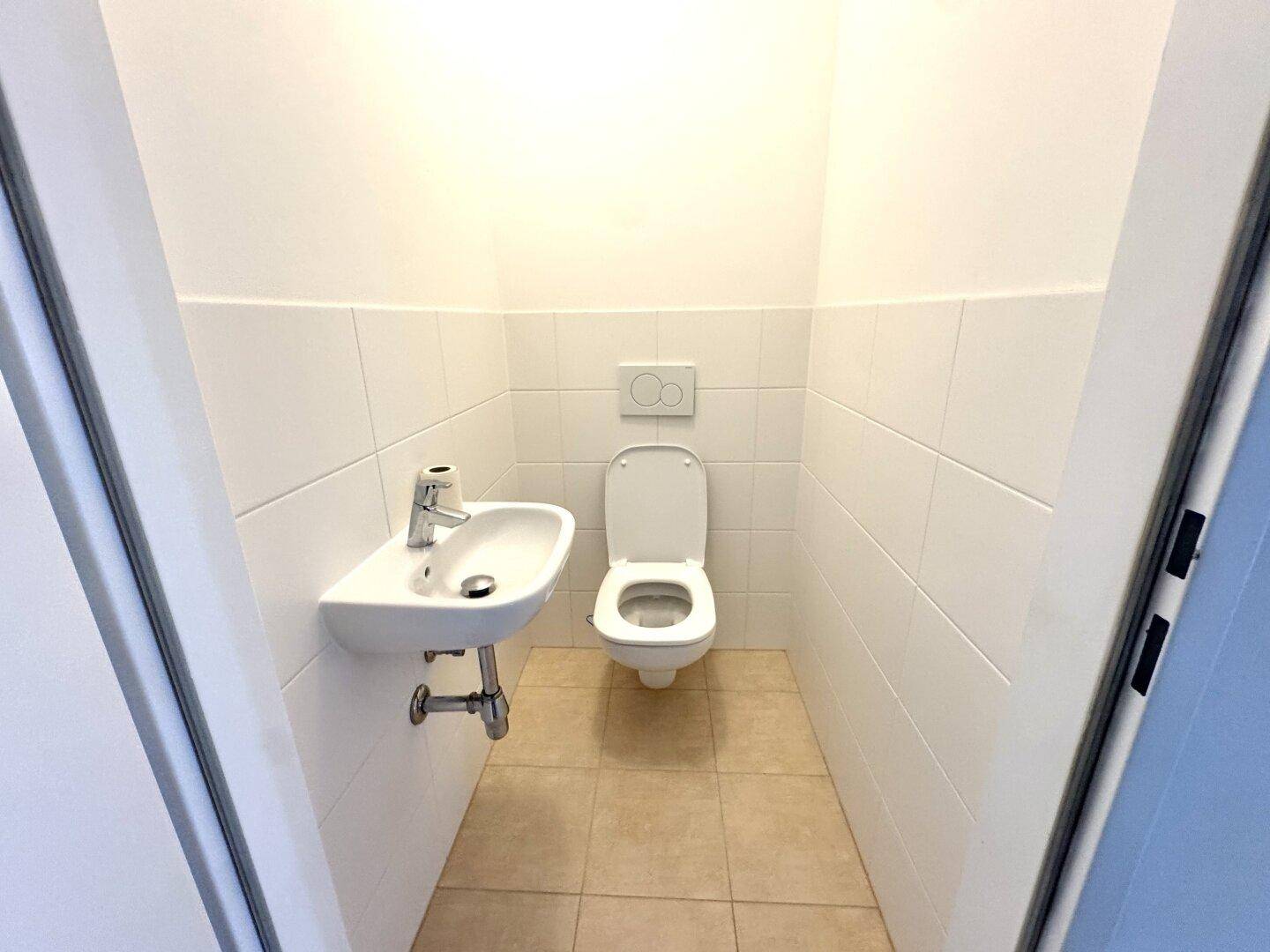 Kompaktes Gäste-WC mit wandhängender Toilette und kleinem Handwaschbecken.