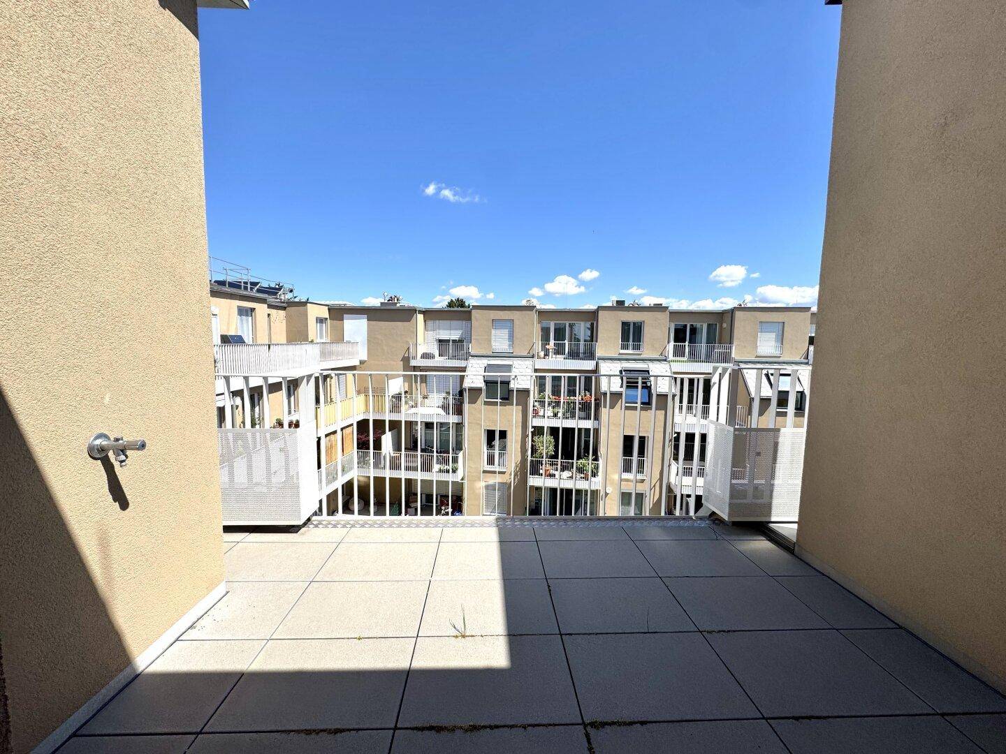 Geräumiger Balkon mit Fliesenboden und Blick auf die umliegenden Gebäude.