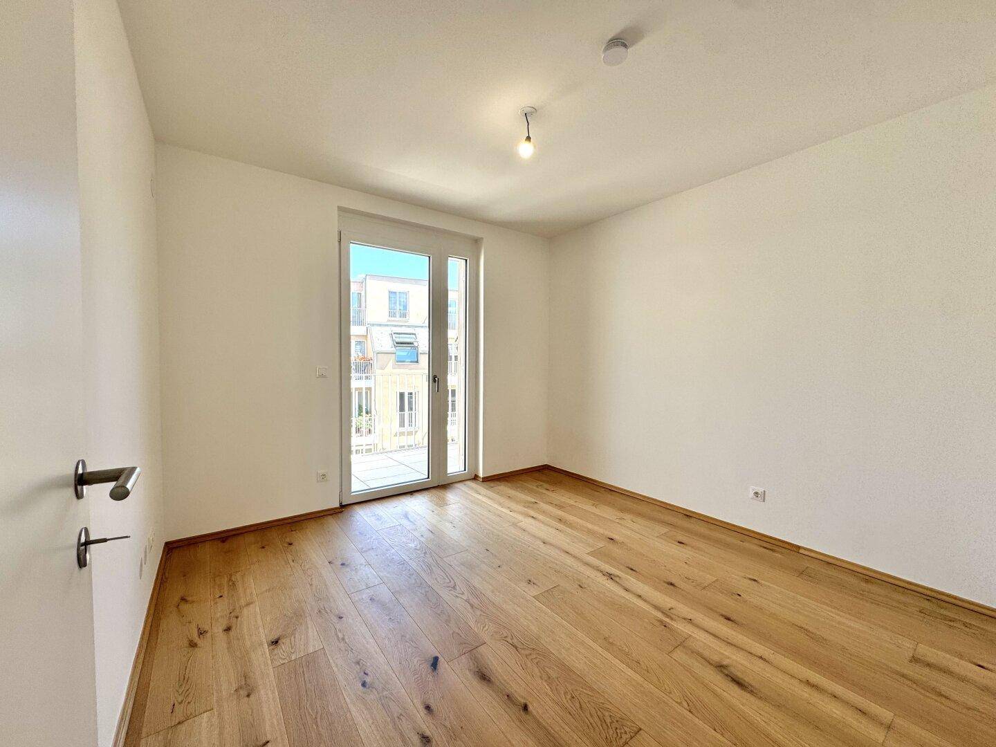 Geräumiges Schlafzimmer mit Eichenparkett und direktem Zugang zu einem sonnigen Balkon.
