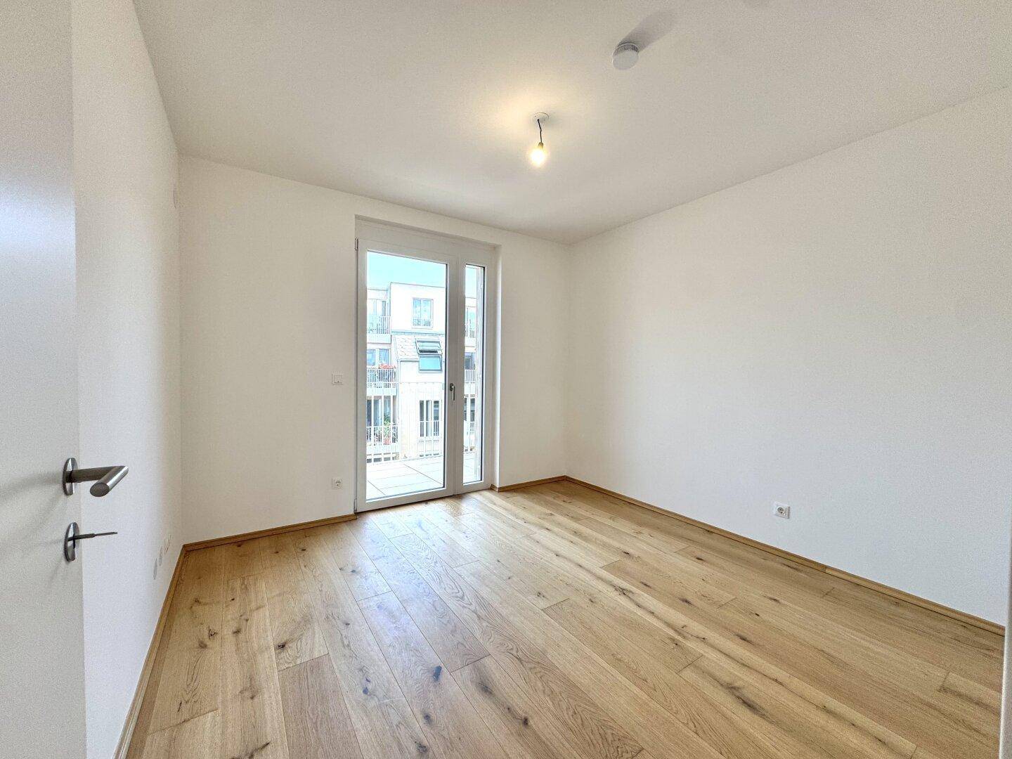 Geräumiges Schlafzimmer mit Eichenparkett und direktem Zugang zu einem sonnigen Balkon.