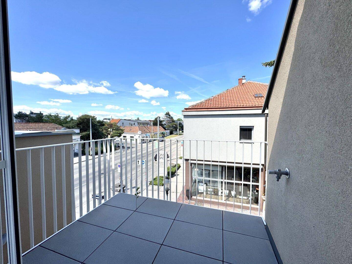 Kleiner Balkon mit Fliesenboden und Blick auf die Straße und umliegende Gebäude.