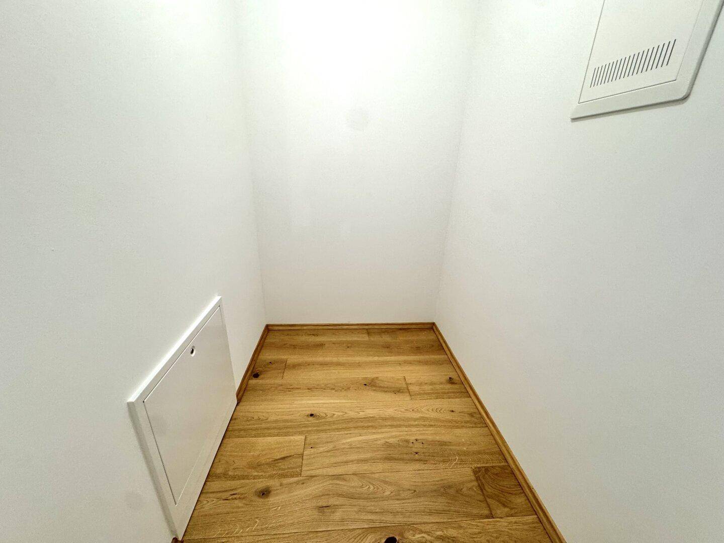 Kleiner Abstellraum mit Holzboden und weißen Wänden, ideal für zusätzlichen Stauraum.