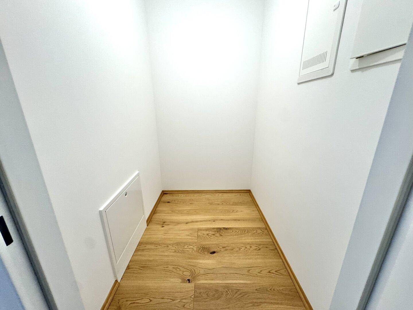 Kleiner Abstellraum mit Holzboden und weißen Wänden, ideal für zusätzlichen Stauraum.