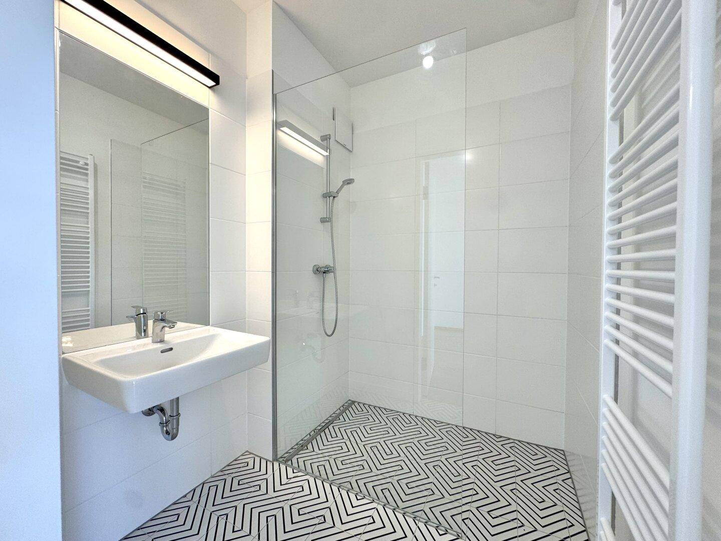 Modernes Badezimmer mit weißen Fliesen, begehbarer Dusche und Heizkörper.