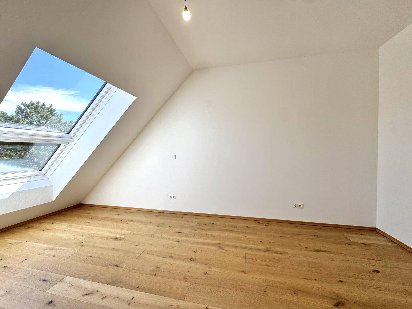 Geräumiges Zimmer mit Holzboden und großem Dachfenster für viel Tageslicht.