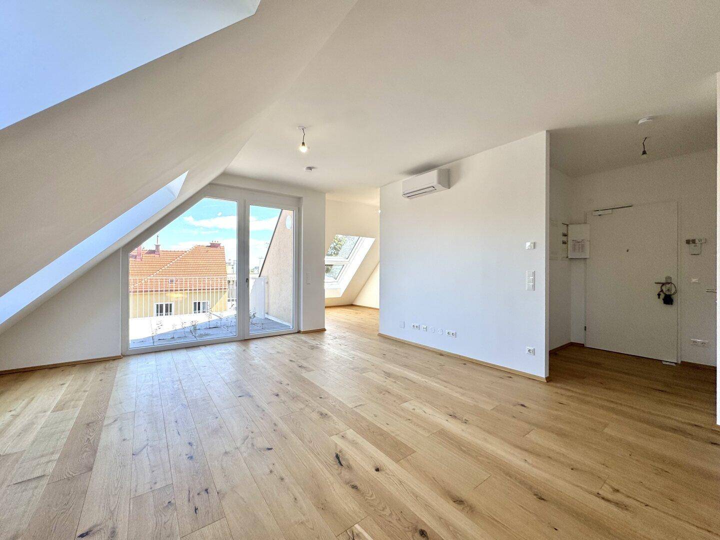 Lichtdurchfluteter Wohnbereich mit Holzboden und Zugang zu einem Balkon.
