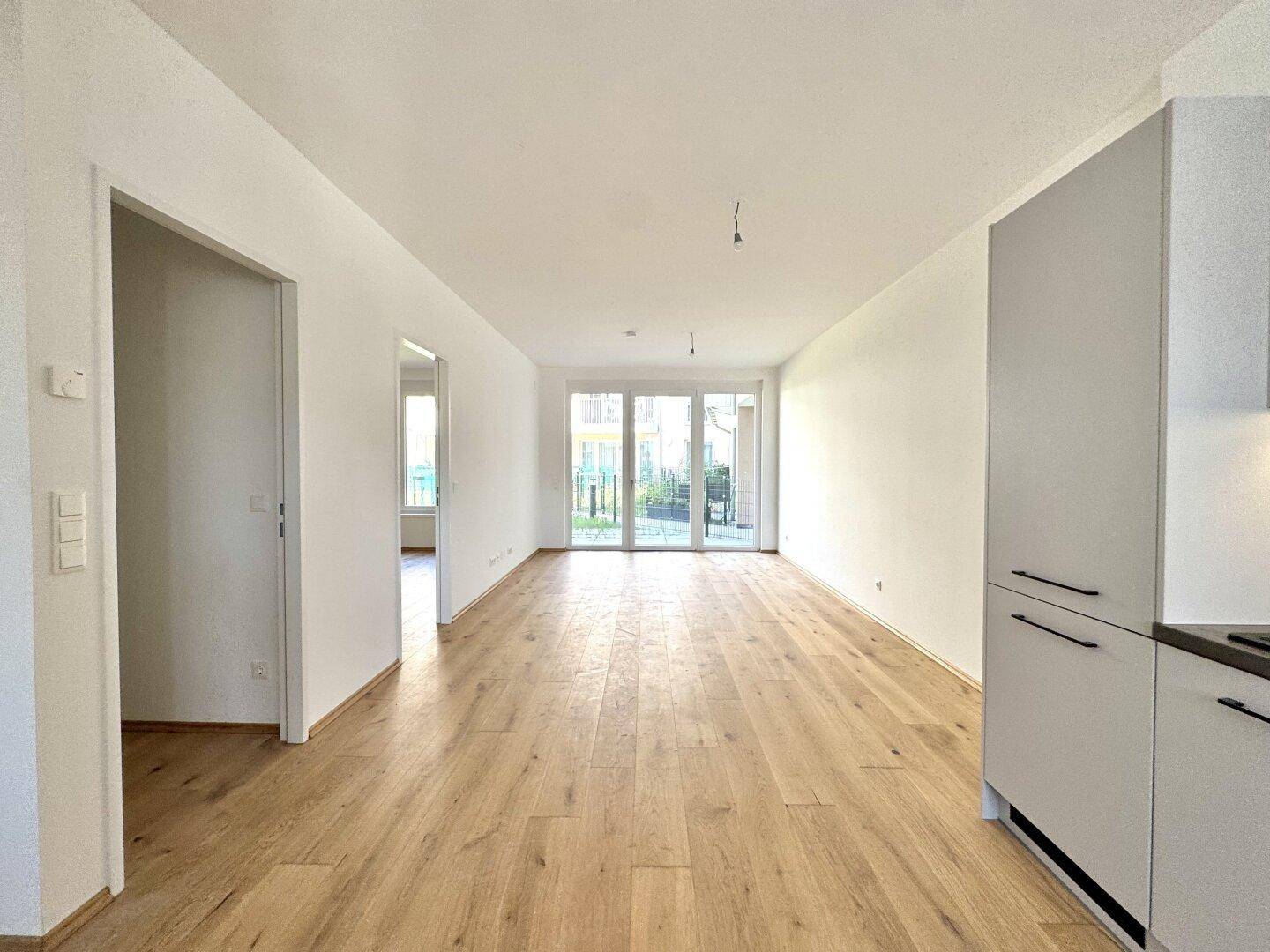 Heller, offener Wohnbereich mit Holzboden und Zugang zu einem Außenbereich.