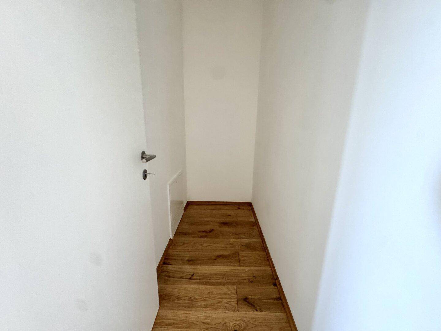 Kleiner Abstellraum mit Holzboden und weiß gestrichenen Wänden.
