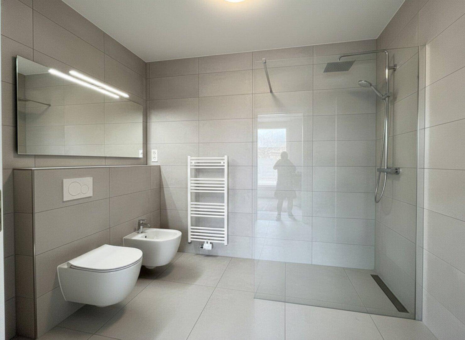 Modernes Badezimmer mit großer begehbarer Dusche, wandhängendem WC und Bidet.