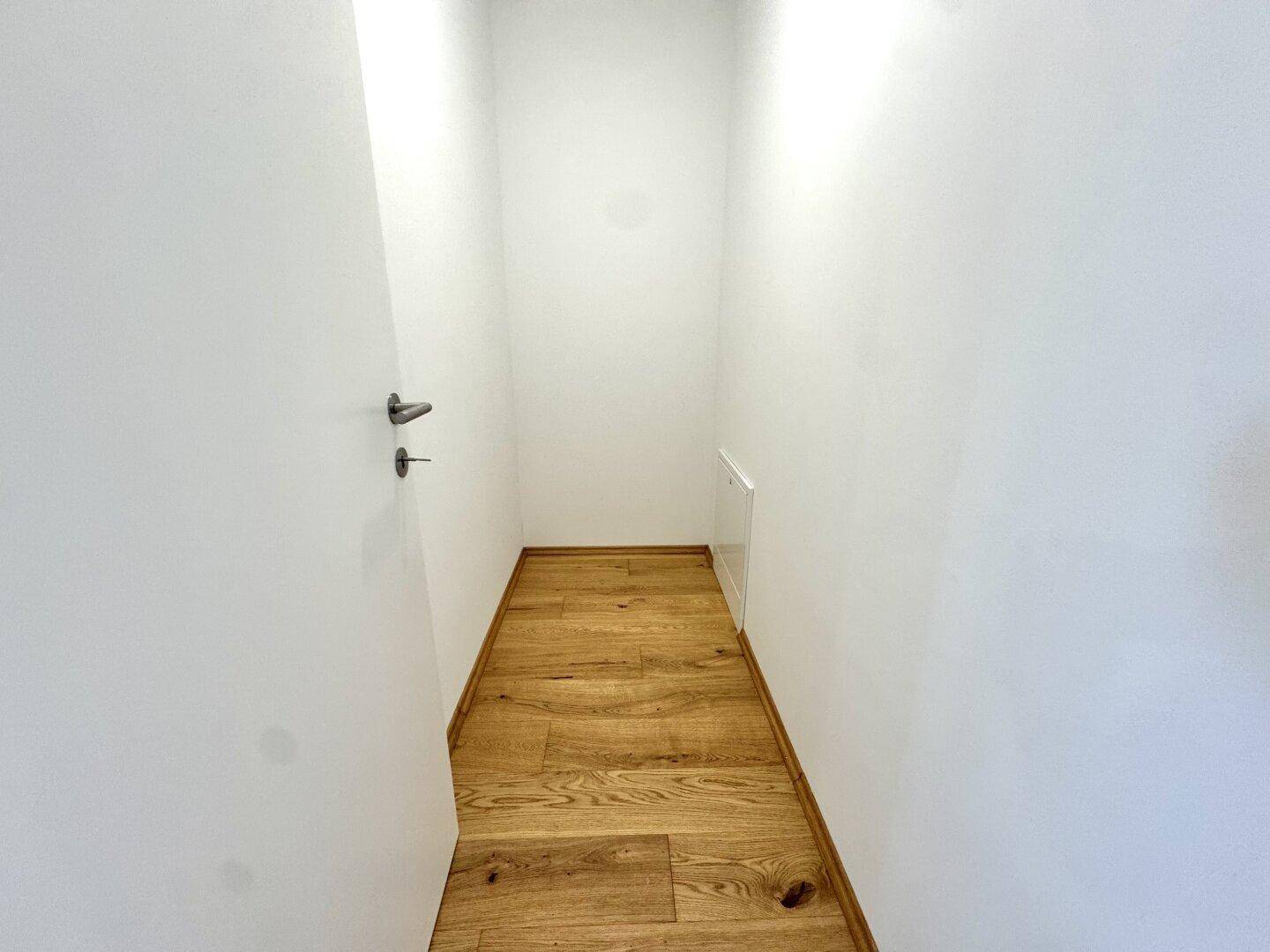 Praktischer Abstellraum mit hellem Holzboden und weißen Wänden für zusätzlichen Stauraum.