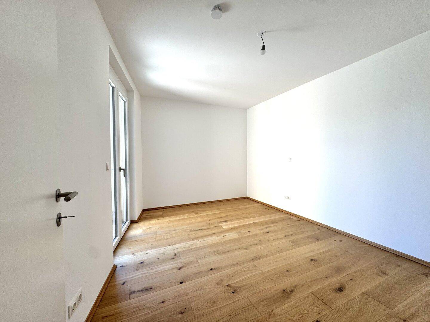 Ruhiges Schlafzimmer mit hellem Eichenparkett und Zugang zu einem privaten Außenbereich.
