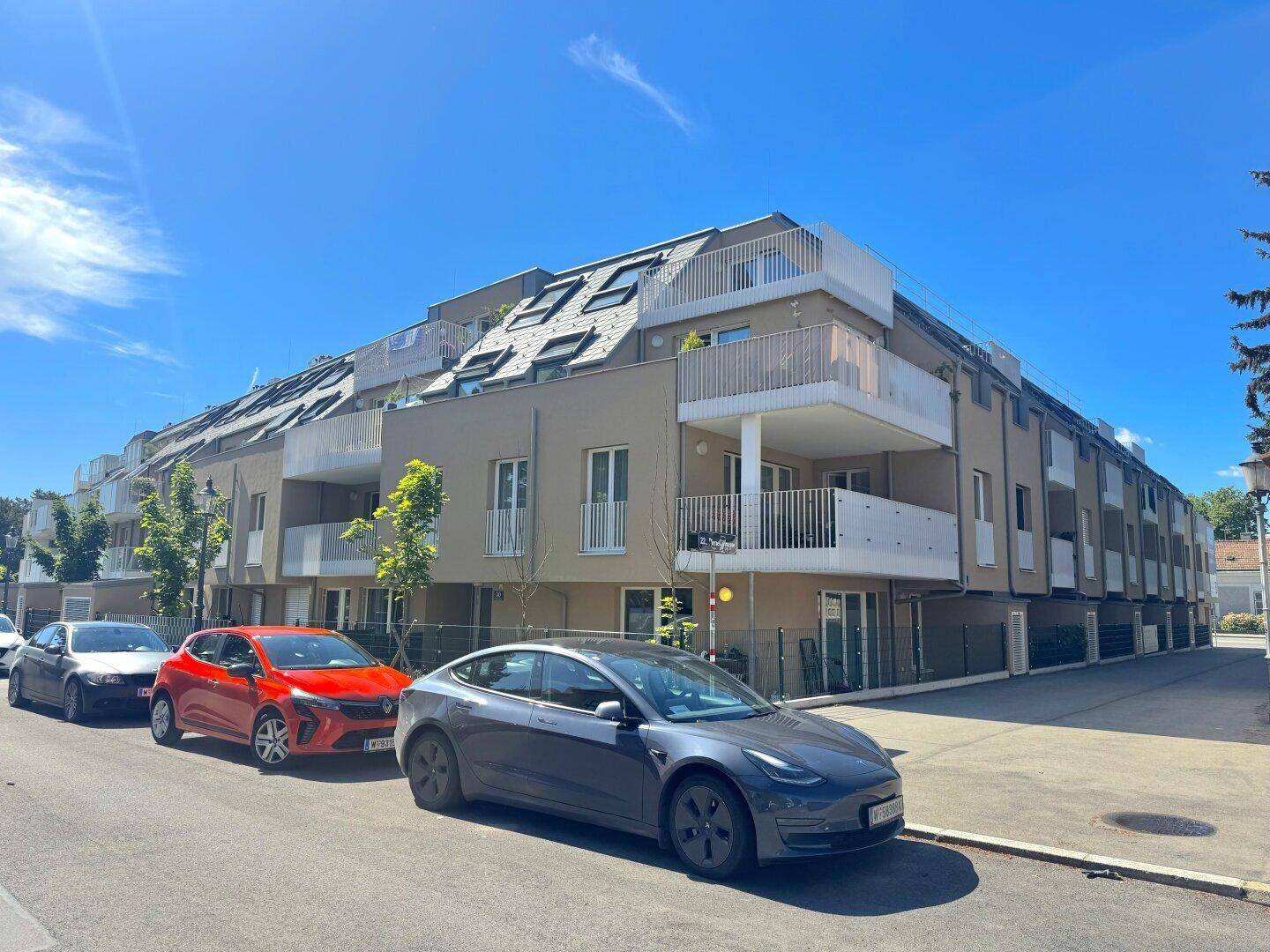 Moderne Wohnanlage mit mehreren Balkonen und zeitgenössischer Architektur unter blauem Himmel.