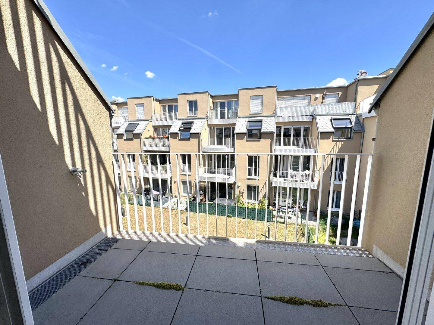 Balkon mit Blick auf den begrünten Innenhof und die modernen Wohngebäude.