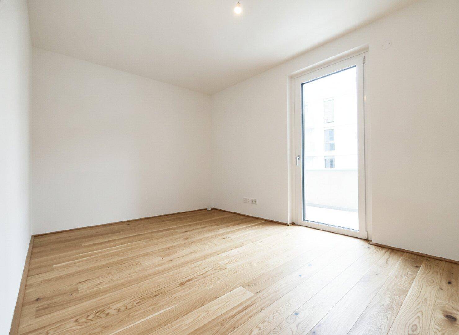 Geräumiges, helles Zimmer mit Parkettboden und großem Fenster, bereit zum Einzug.