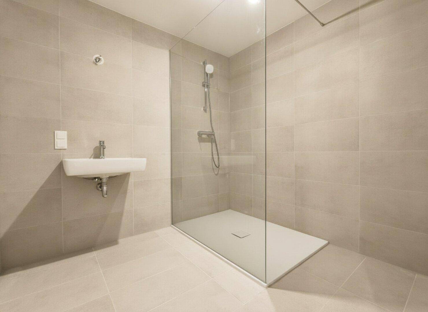 Modernes Badezimmer mit beigefarbenen Fliesen, ebenerdiger Dusche und kleinem Waschbecken.