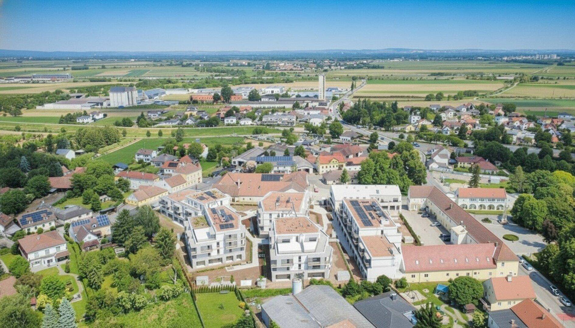 Weitläufige Luftaufnahme der Wohnanlage eingebettet in eine ländliche Umgebung mit Feldern.