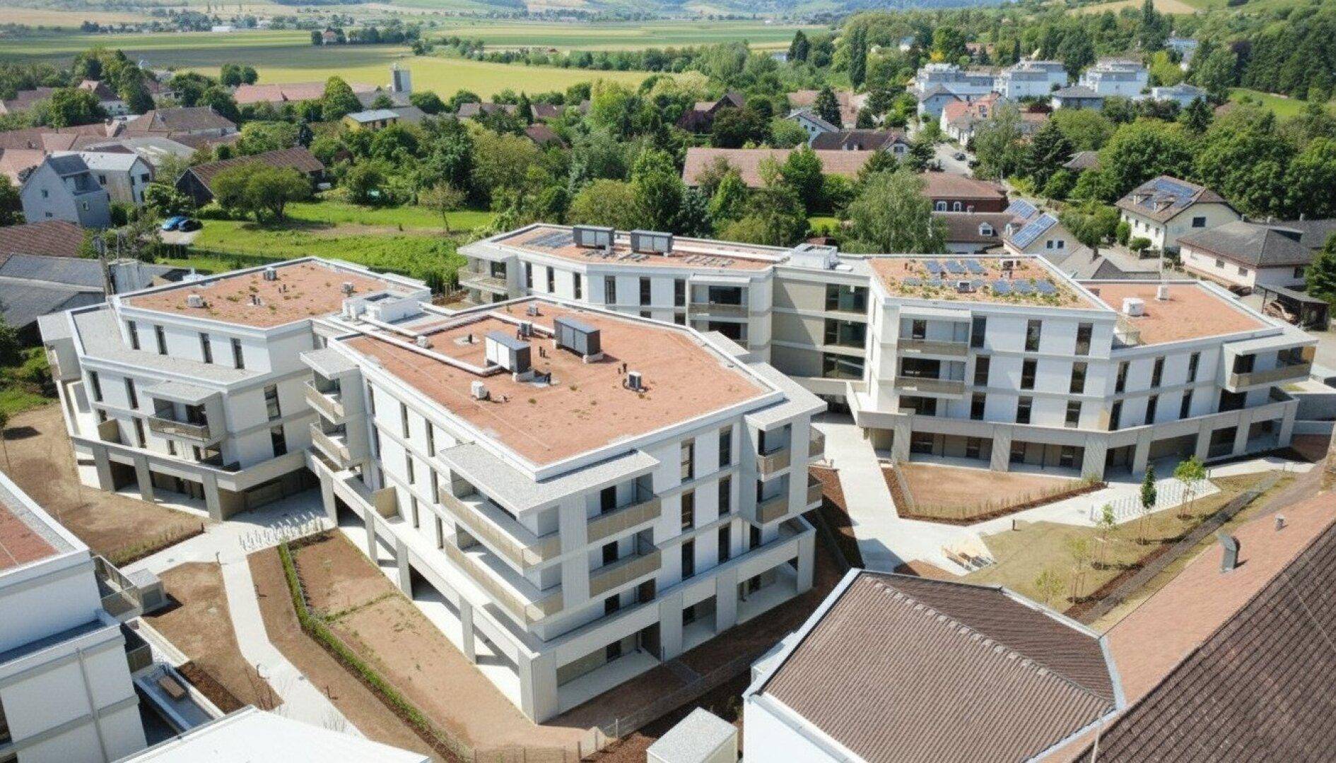 Vogelperspektive auf die moderne Wohnanlage mit Flachdächern und integrierten Solaranlagen.