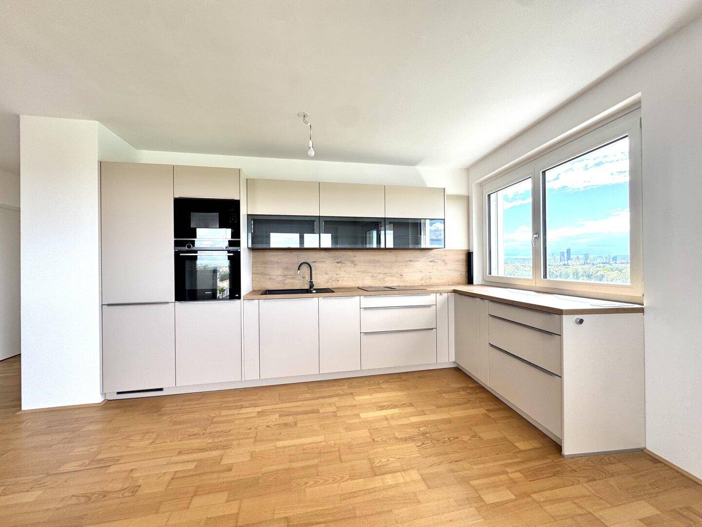 Moderne Einbauküche in hellem Design mit integrierten Geräten und Holz-Arbeitsplatte.