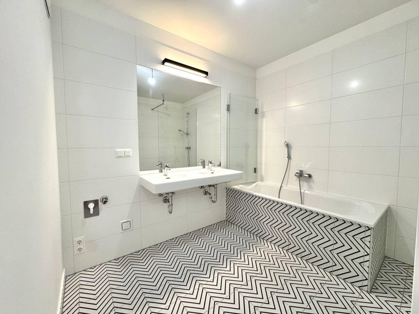 Modernes Badezimmer mit Doppelwaschbecken, Badewanne und Duschbereich.