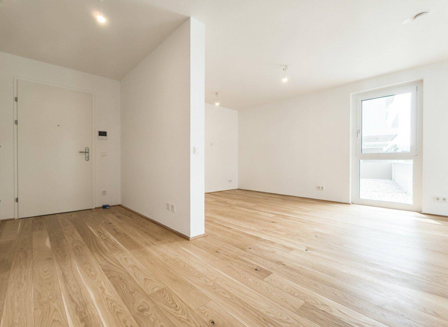 Heller Eingangsbereich mit Holzboden, der in einen offenen Wohnbereich übergeht.