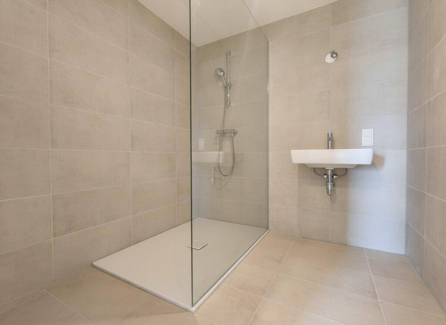 Modernes Badezimmer mit begehbarer Dusche, Wandfliesen und einem schwebenden Waschbecken.