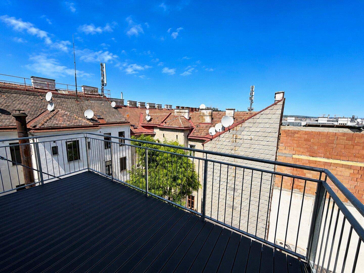 Sonniger Balkon mit Blick auf die umliegenden Dächer und Antennen der Stadt.