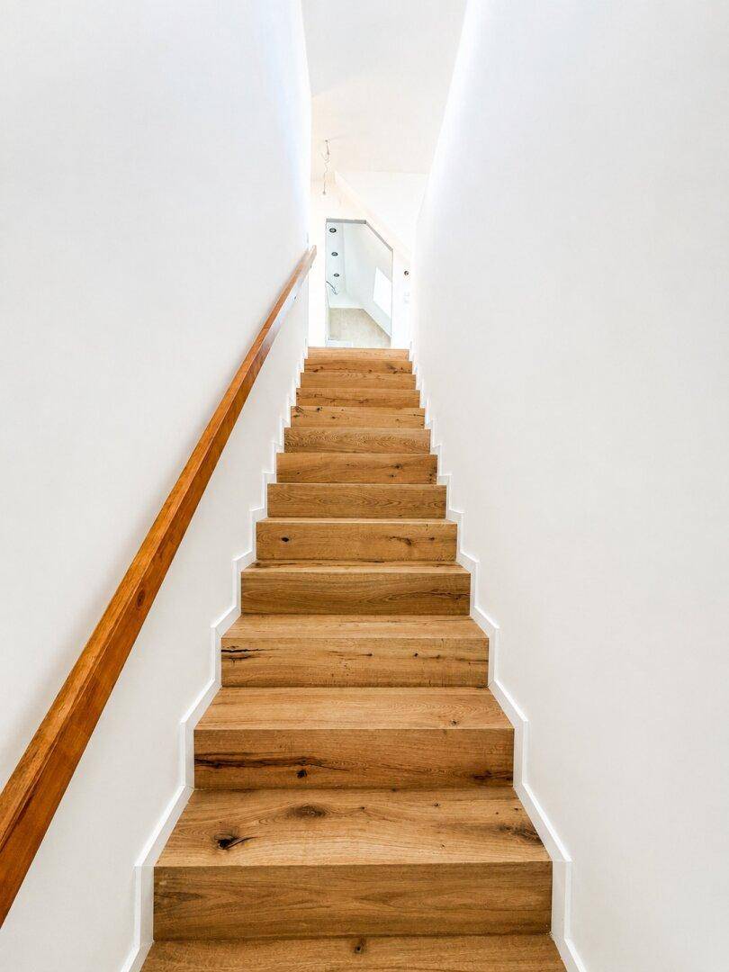 Elegante Holztreppe mit passendem Handlauf, die die verschiedenen Ebenen verbindet.