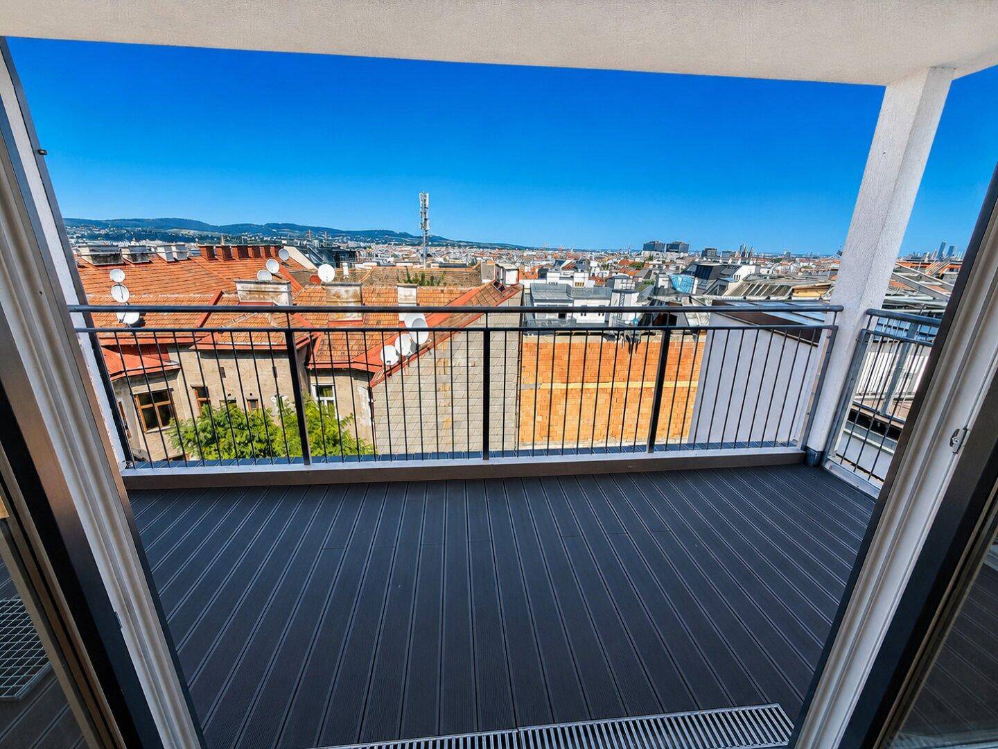 Heller Balkon mit moderner Reling und Panoramablick über die Dächer der Stadt.