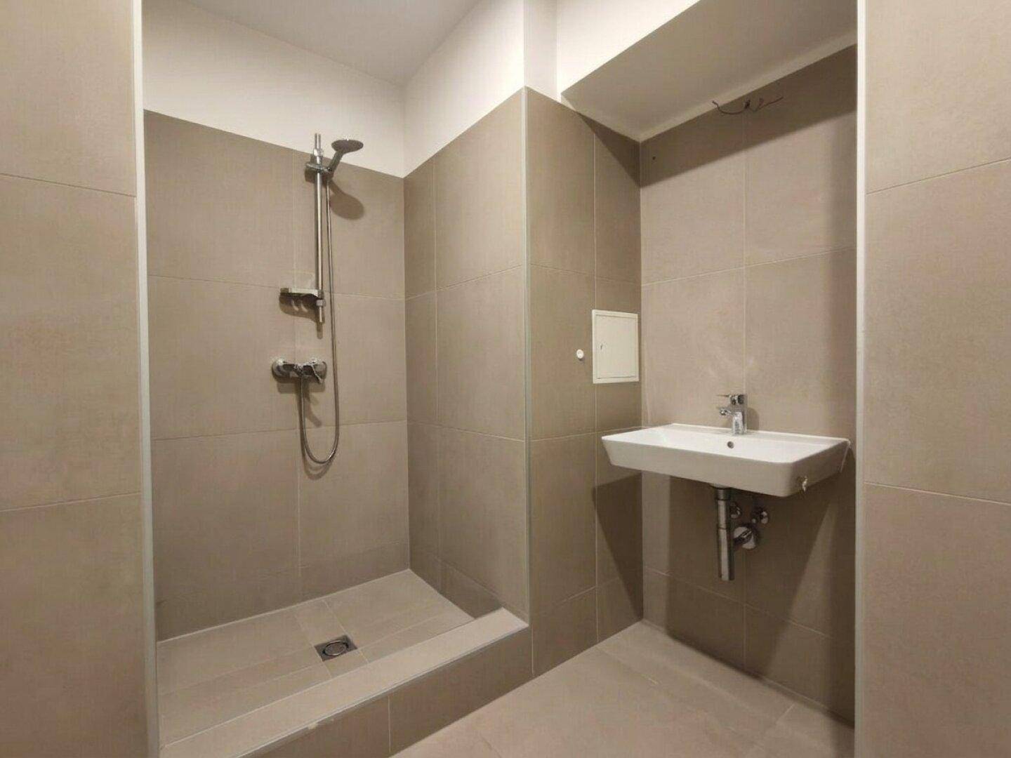 Modernes Badezimmer mit ebenerdiger Dusche und wandmontiertem Waschbecken.