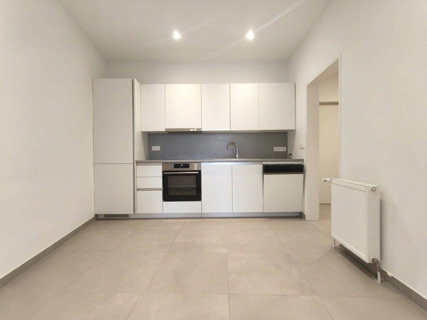 Moderne Einbauküche in Weiß mit integrierten Geräten und Fliesenboden.