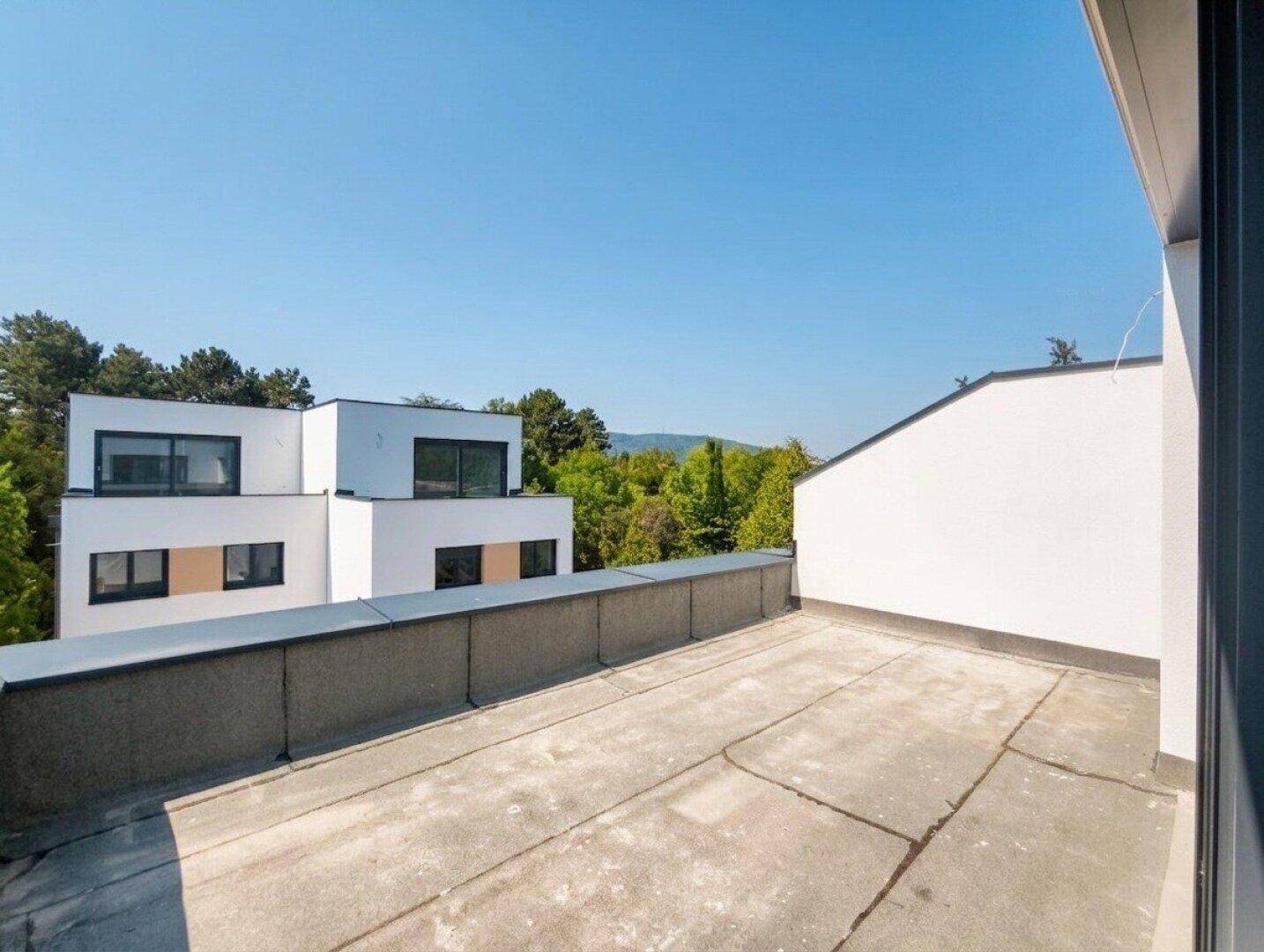 Weitläufige Dachterrasse mit Panoramablick auf die umliegende Natur und moderne Gebäude.