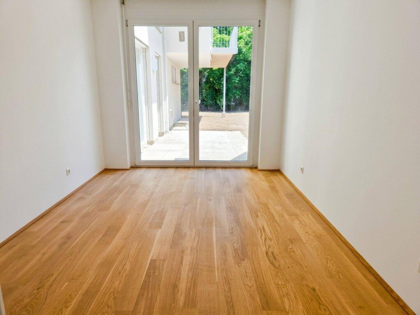 Lichtdurchfluteter Wohnraum mit Parkettboden und direktem Zugang zum Gartenbereich.