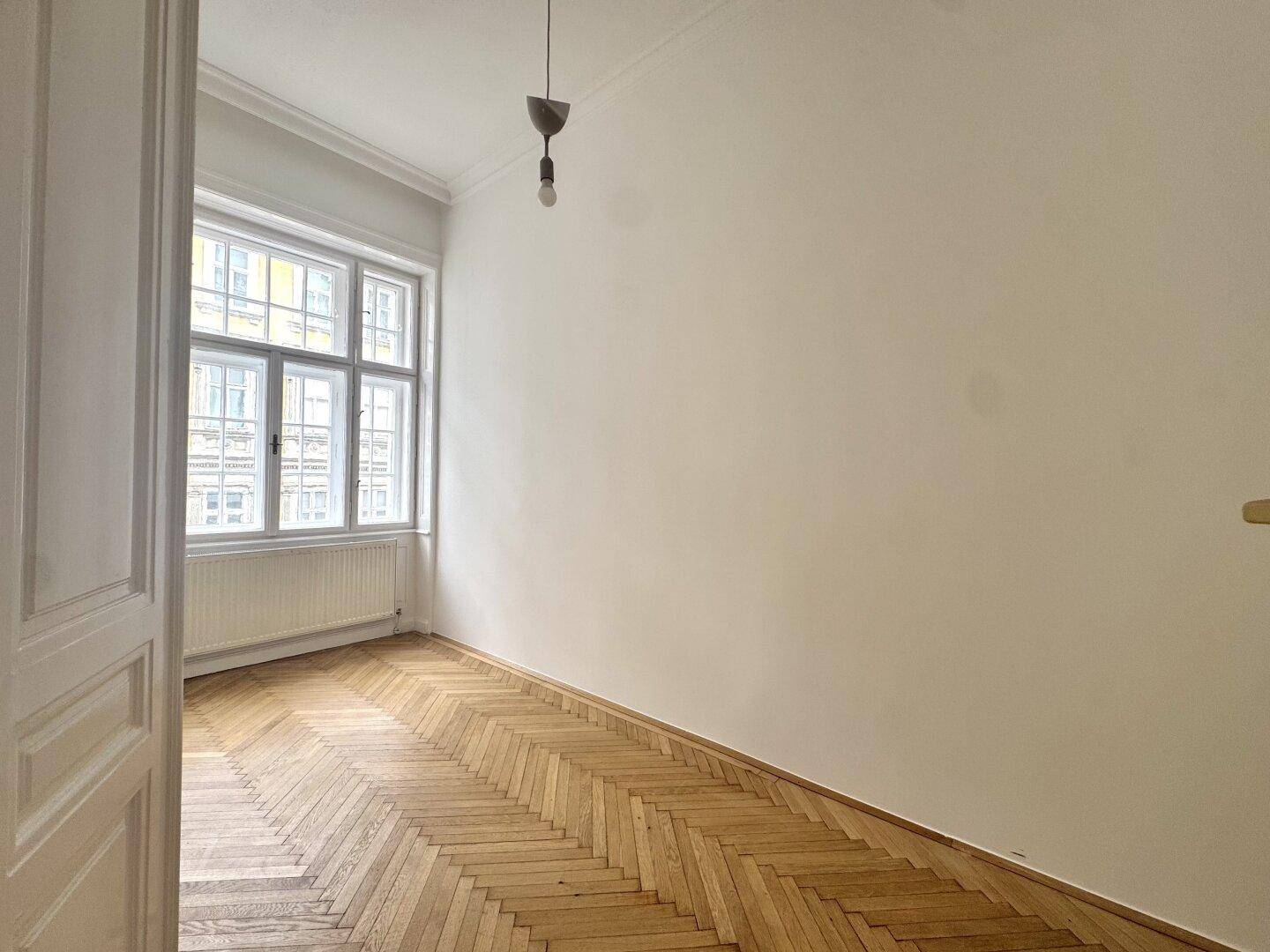 Gemütliches Zimmer mit Fischgrätparkett und einem Fenster, ideal als Schlaf- oder Arbeitszimmer.