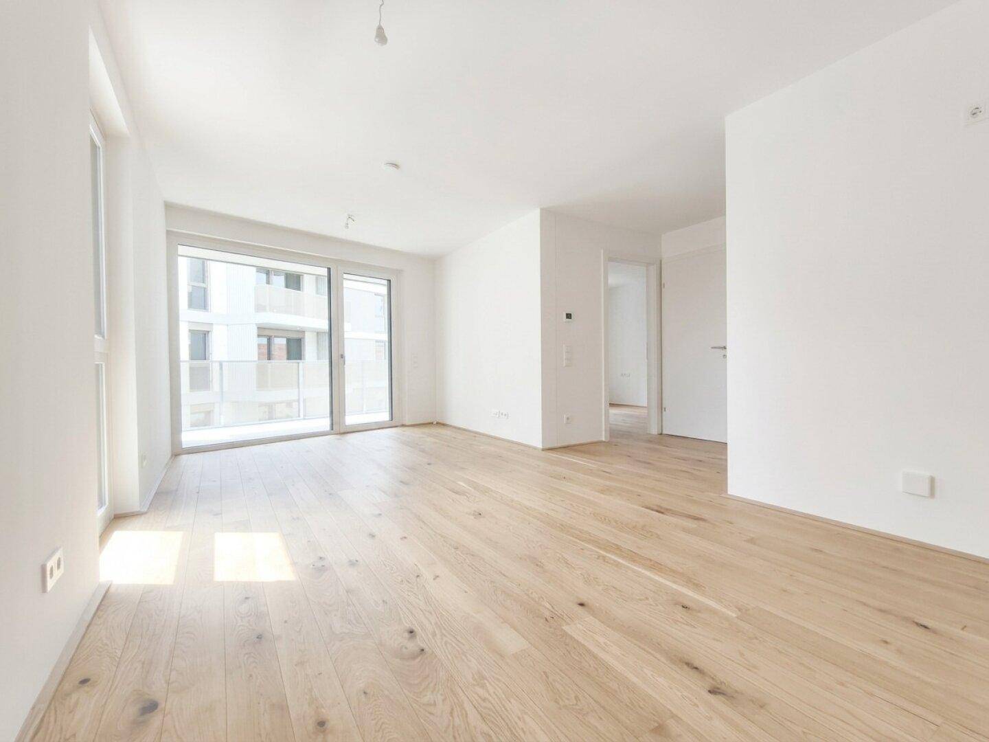 Geräumiges, helles Wohnzimmer mit Eichenparkett und großen Fenstern, bereit zur Einrichtung.