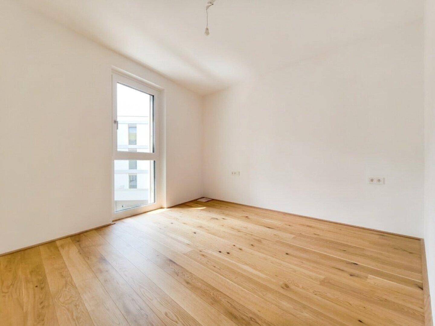 Freundliches Zimmer mit Eichenparkett und großem Fenster, ideal als Schlaf- oder Arbeitszimmer.