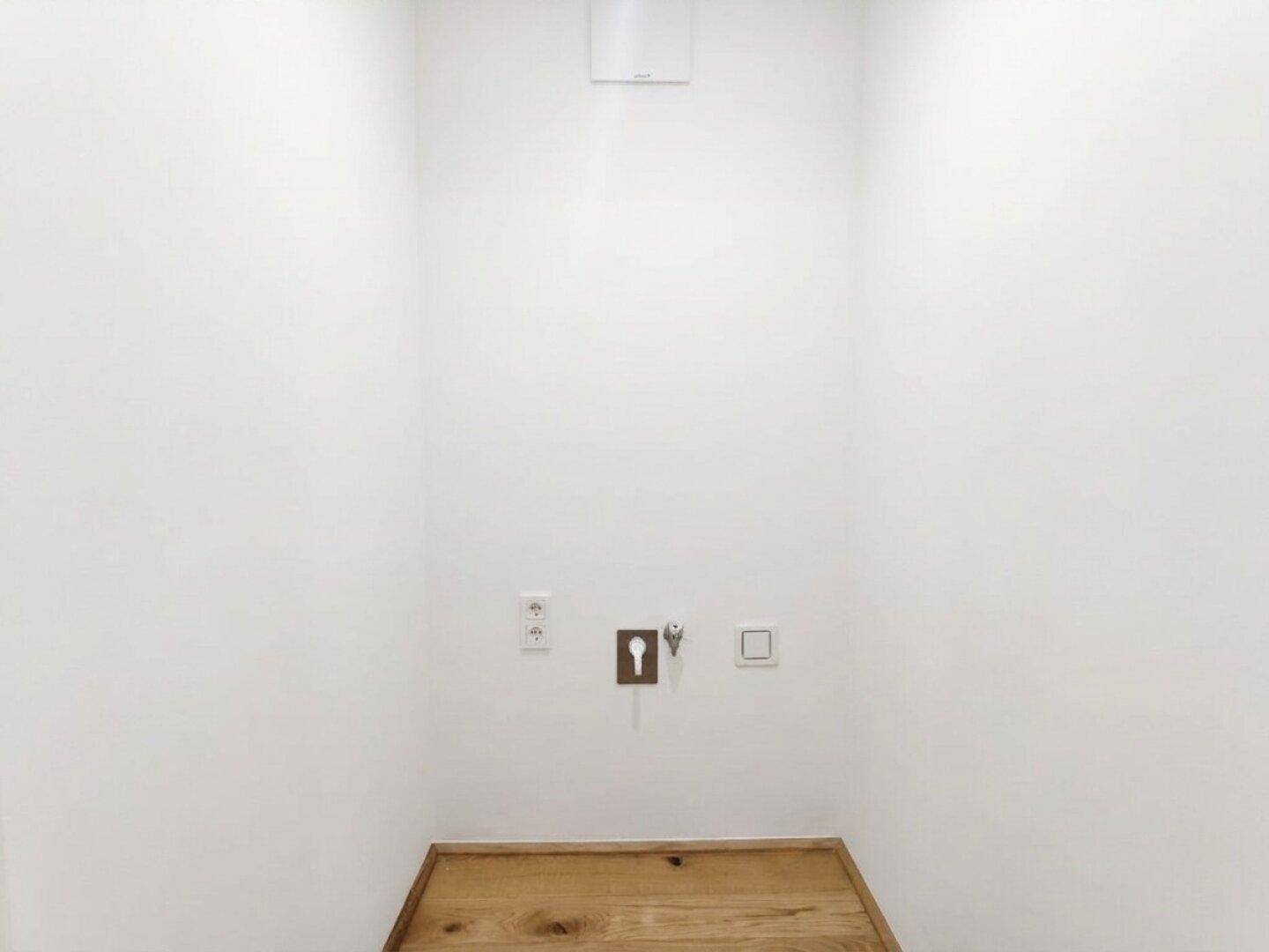 Kleiner Hauswirtschaftsraum mit Anschlüssen für Waschmaschine und Trockner sowie Holzboden.