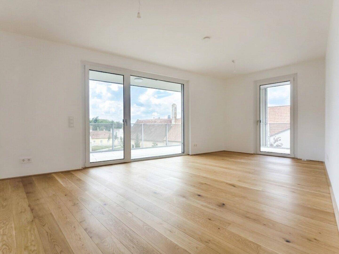 Geräumiger, heller Raum mit Holzplankenboden und weitem Blick über die Dächer und ins Grüne.