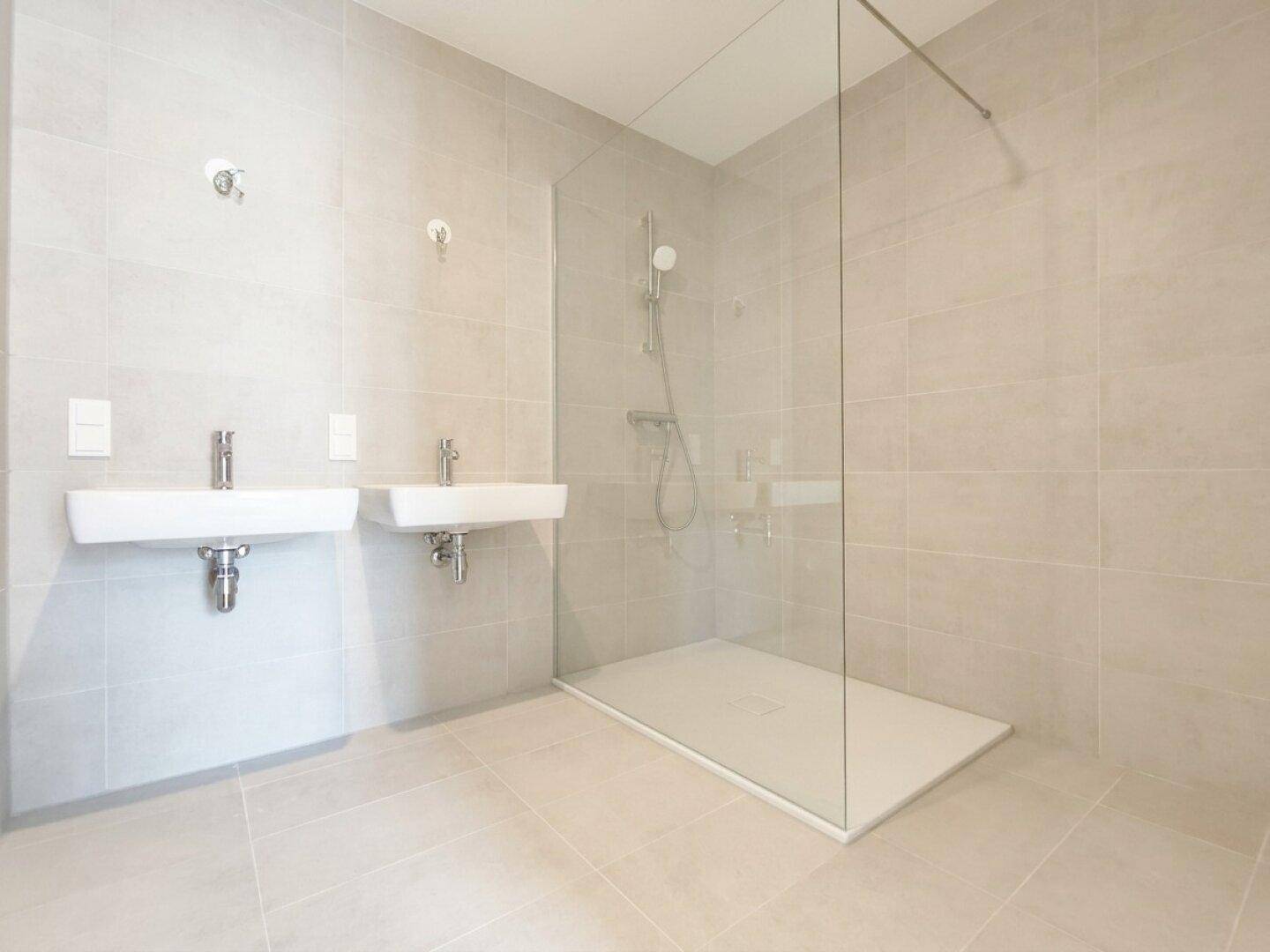 Modernes Badezimmer mit zwei Waschbecken und einer geräumigen ebenerdigen Dusche.