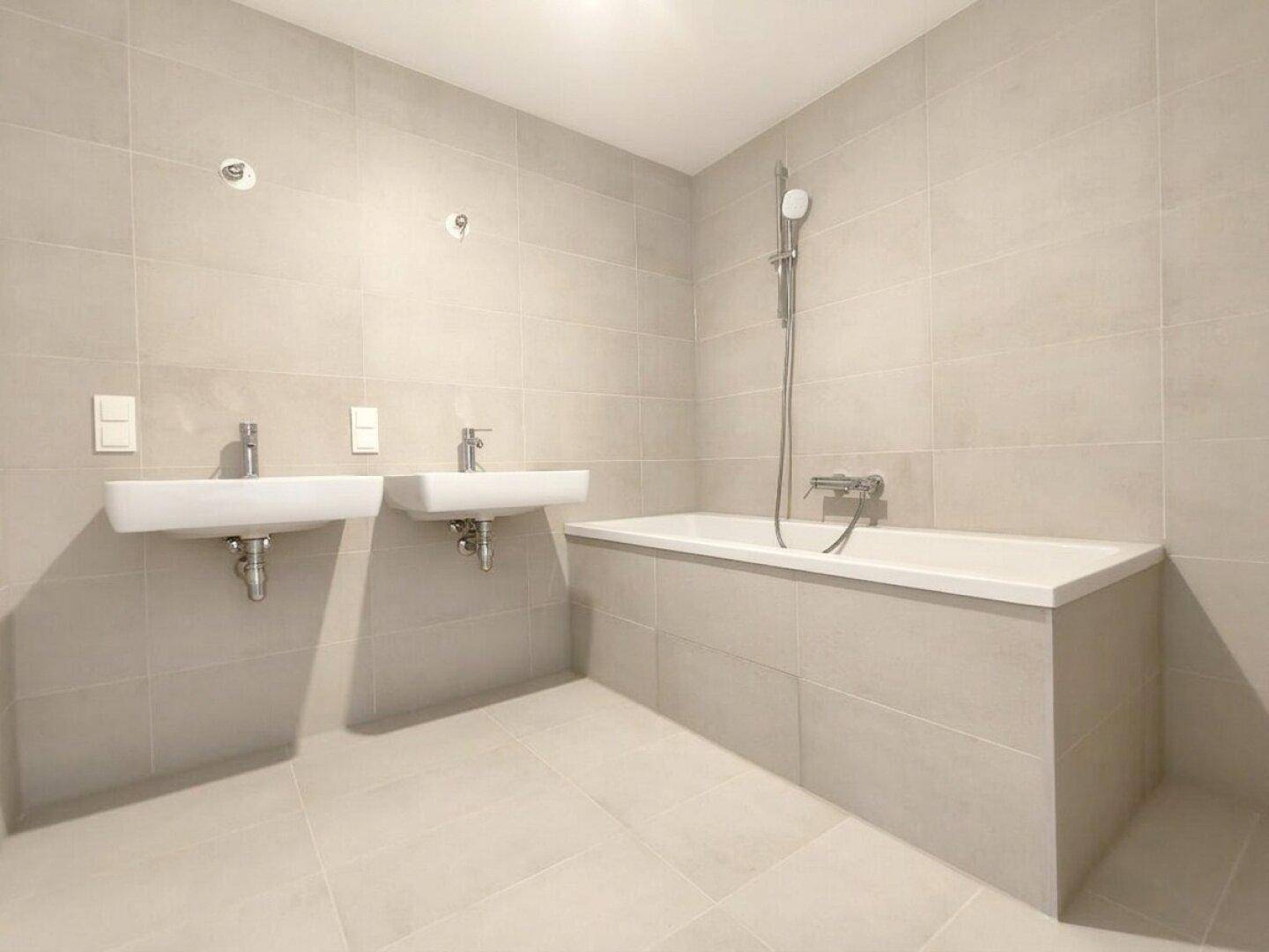 Helles Badezimmer mit zwei Waschbecken und einer elegant integrierten Badewanne.