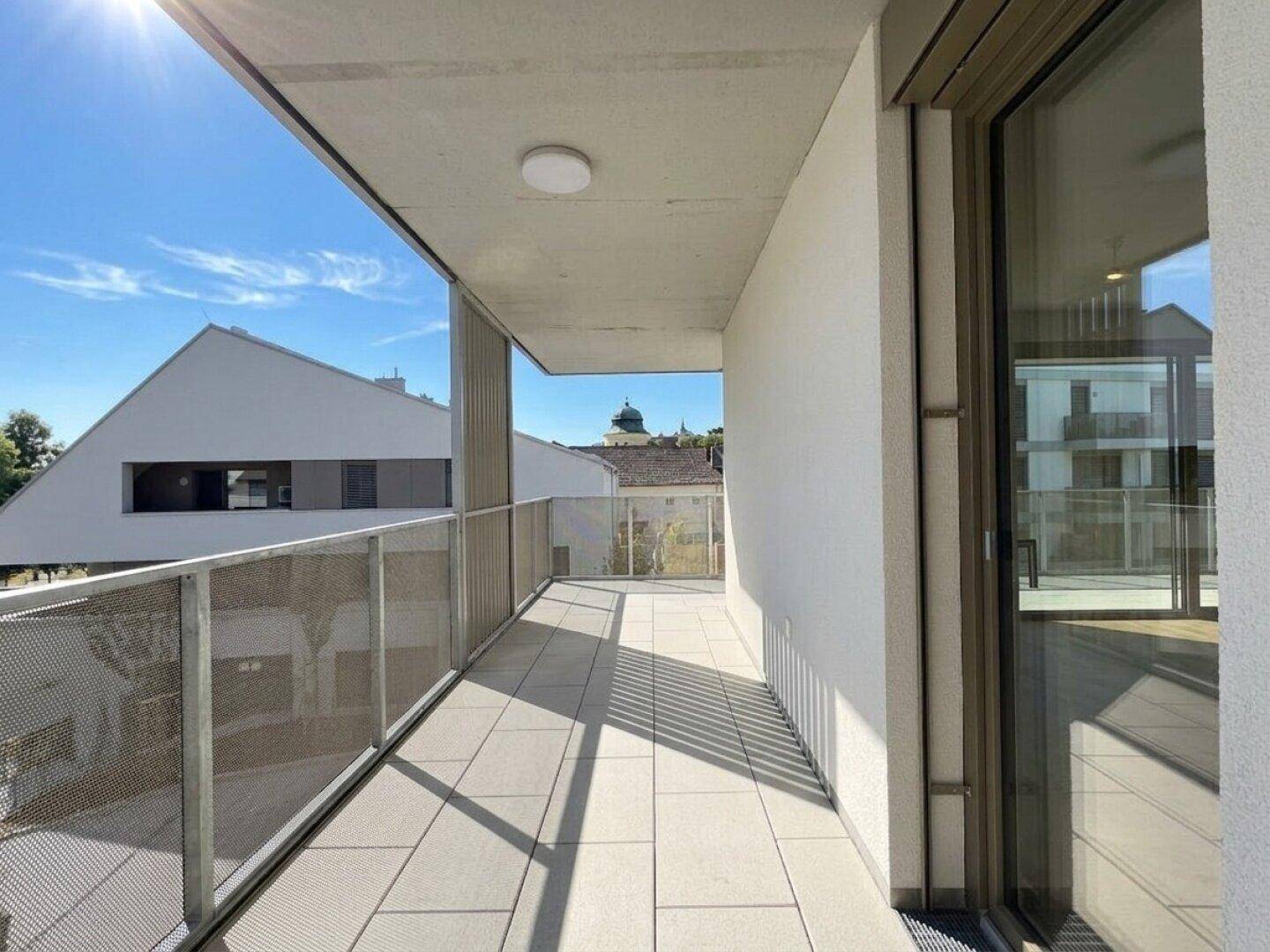 Geräumiger Balkon mit moderner Architektur und viel Sonnenlicht, ideal zum Entspannen.
